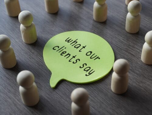 A group of wooden figurines surrounding a speech bubble with text WHAT OUR CLIENTS SAY.