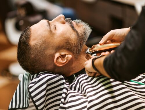 Barber trims the beard of the customer